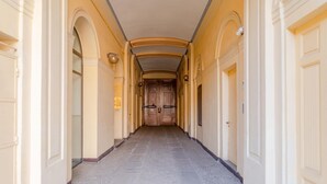 A long, narrow hallway with arched doorways and a central wooden door at the end. - Casa Mimmo by Happyhostorino (Turin)