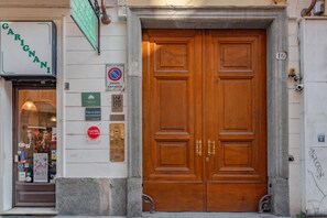 Une porte en bois à deux battants, ornée d’une plaque et d’un panneau indiquant qu’il est interdit de se garer.