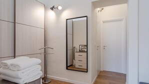 Une salle de bain moderne avec un meuble-lavabo en bois, un grand miroir et une porte donnant sur une autre pièce.