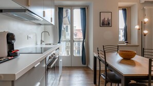 Une cuisine moderne équipée d’un four encastré, d’une machine à café et d’un coin repas avec une table et des chaises en bois.