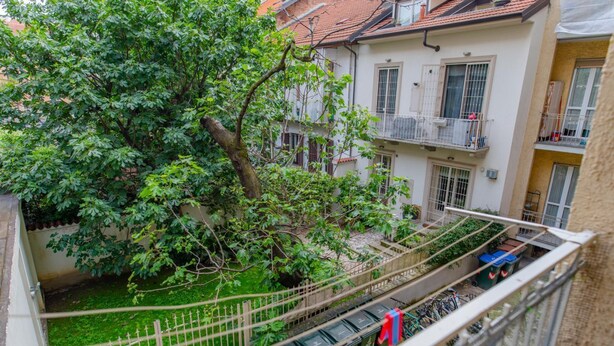 A courtyard with a tree, a fence, and a building with balconies. - Perrero4 by Happyhostorino (Torino)