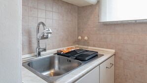 A kitchen with a stainless steel sink, a built-in oven, and a white cabinet. - Perrero4 by Happyhostorino (Torino)