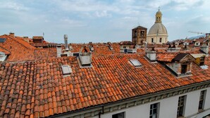A rooftop with terracotta tiles, a white building with multiple windows, and a dome structure in the background.