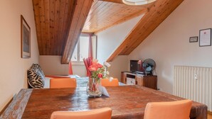 A dining area with a wooden table, orange chairs, a vase of flowers, and a ceiling fan.