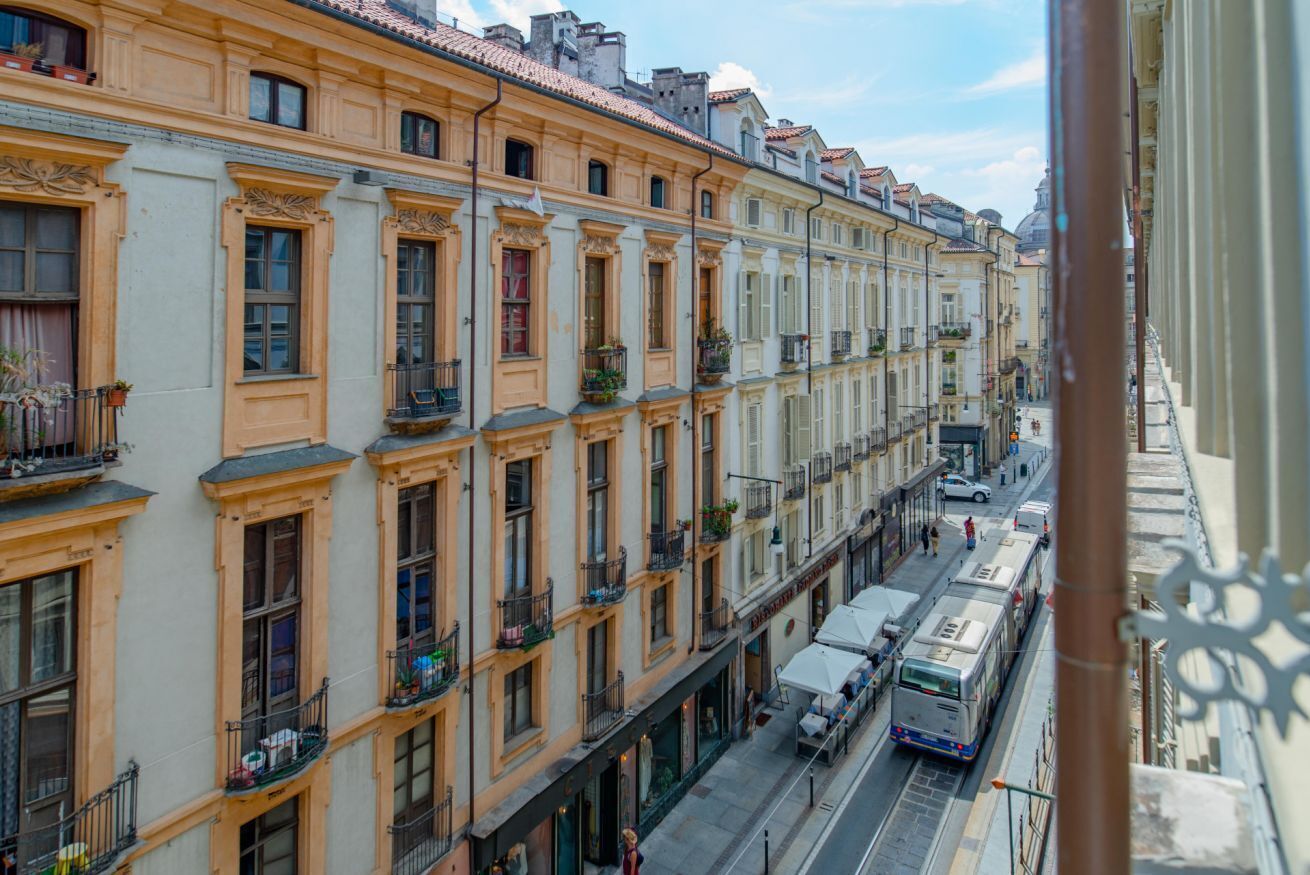 A row of historic buildings with uniform balconies and a tram passing by.