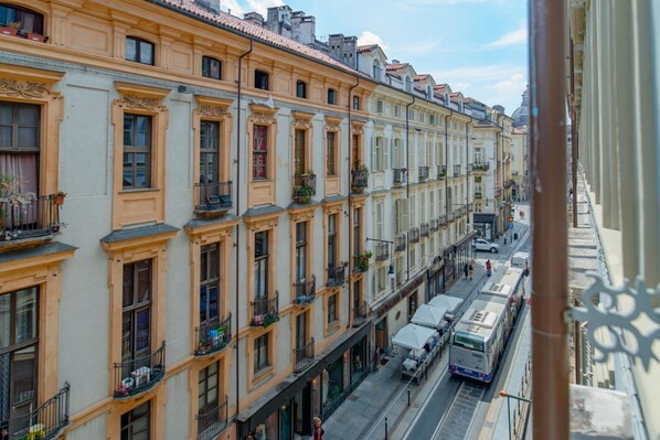 A row of historic buildings with uniform balconies and a tram passing by.