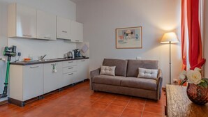A compact living space with a kitchenette, a sofa, a painting, and a lamp. - San Domenico_222 by Happyhostorino (Torino)
