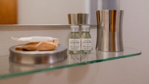 A bathroom counter with two bottles of aloe vera juice and a metallic container. - San Domenico_222 by Happyhostorino (Torino)