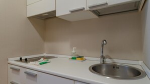 A small kitchenette with a stainless steel sink, a faucet, and a countertop with a soap dispenser and sponge.
