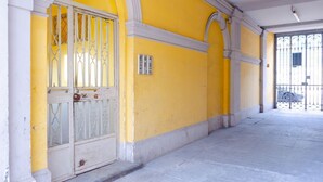 A yellow building with a white door and metal bars, a tiled floor, and a white column. - Balon Turin View (Airco, Centrale)  (Torino)