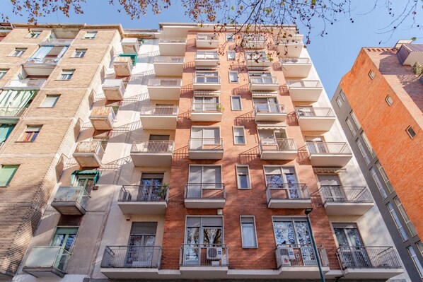 A multi-story residential building with balconies, windows, and a brick facade.