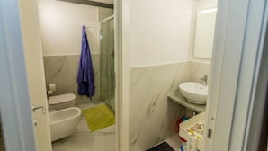 A bathroom with a toilet, bidet, and a sink.