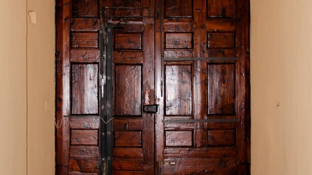 Una puerta doble de madera grande con un picaporte y un cerrojo de metal.