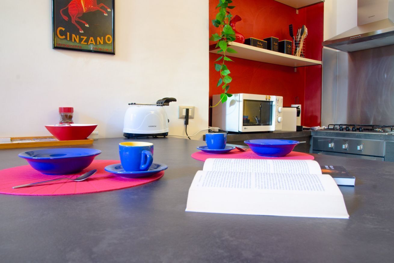 A kitchen with a red wall, a white microwave, a gas stove, and a sink.