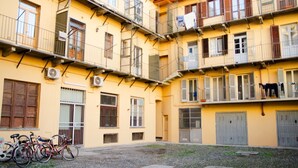 Un edificio amarillo de varios pisos con balcones, unidades de aire acondicionado y bicicletas estacionadas afuera.