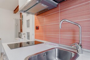 A modern kitchen with a stainless steel sink, a built-in oven, and a red-tiled backsplash. - [monolocale, Wifi] Casa Amely (Torino)