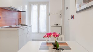 Een moderne keuken met witte kasten, een roestvrijstalen afzuigkap en een raam met dunne gordijnen.