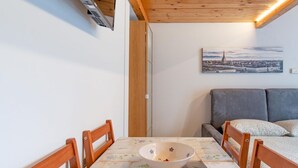 Ett kompakt rum med ett matbord, stolar, en soffa och en tavla som föreställer en stadsbild.