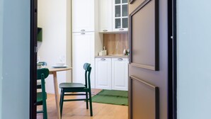 Eine kleine Küche mit weißen Schränken, einer Holz Arbeitsplatte und einer grünen Fußmatte.