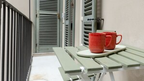 Ein grüner Tisch im Freien mit zwei roten Tassen auf einem weißen Tablett.