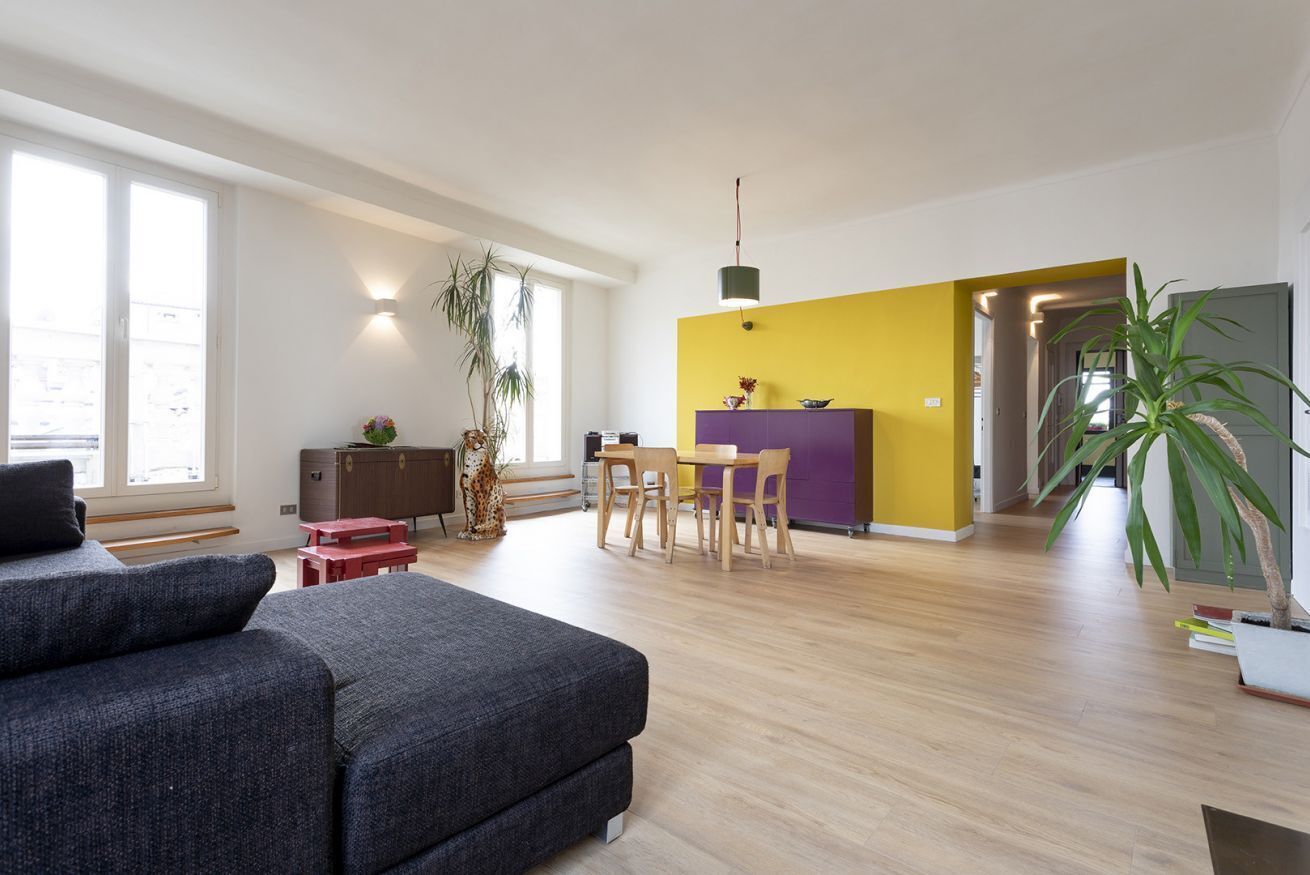 Una sala moderna con sofá, un comedor con sillas y una mesa, y una cocina con un armario púrpura.
