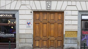 A building facade with a large wooden double door, a storefront with a sign, and a no parking sign.