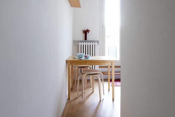 A small dining area with a wooden table and two chairs, a radiator, and a window with natural light. - Attico con vista sulla Consolata (Torino)