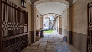 A narrow stone corridor with a metal gate on the left and a staircase leading to a residential area.