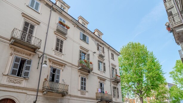 A multi-story building with balconies, a street lamp, and a tree.