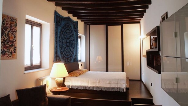 Un dormitorio con cama, lámpara, tapiz y vista al exterior.