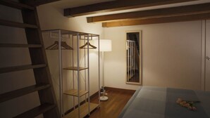 A bedroom with a bed, a wooden ladder, a metal shelving unit, a floor lamp, and a mirror on the wall.