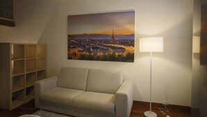 A living room with a sofa, a lamp, and a cityscape painting on the wall.