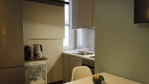 A compact kitchen with a refrigerator, a coffee maker, a sink, and a window.