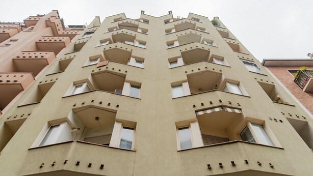 Un edificio de gran altura con una fachada simétrica, múltiples balcones y un estilo arquitectónico uniforme.