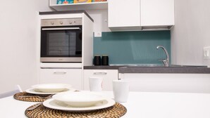 Eine moderne Küche mit weißen Schränken, einem Edelstahlbackofen und einer türkisblauen Spritzschutzwand.