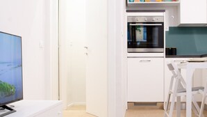 Eine moderne Küche mit weißen Schränken, einem eingebauten Ofen und einem Essbereich mit weißem Tisch und Stühlen.