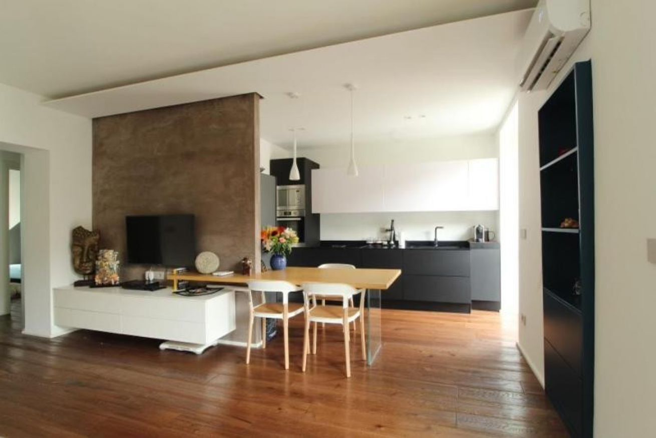 Un salon moderne avec un plancher en bois, un meuble de rangement blanc pour les appareils électroniques et un coin repas comprenant une table et des chaises.