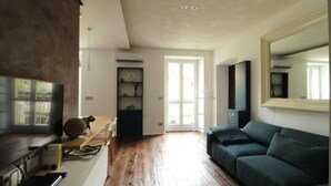 A spacious living area with a wooden floor, a dark green sofa, a flat-screen TV, and a large mirror. - The Nest by Happyhstorino (Torino)