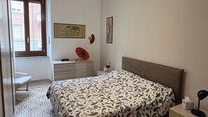 Ett sovrum med en säng, ett skrivbord, en stol, ett fönster och en dörr.