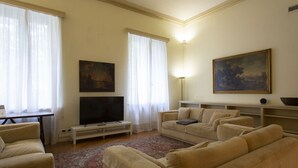 Un salon avec des canapés de couleur beige, un téléviseur à écran plat, un tableau et une lampe.