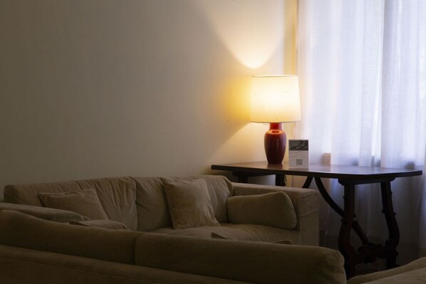 A cozy room with a sofa, a table with a lamp, and a window with sheer curtains. - N10, Luxury, by HappyHosTorino (Torino)