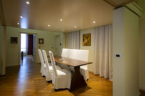 A dining area with a wooden table and white chairs, a white sofa, and a painting on the wall. - N10, Luxury, by HappyHosTorino (Torino)