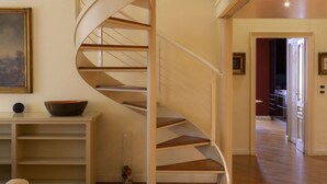 Un escalier en colimaçon avec des marches en bois et des rampes blanches, dans un intérieur moderne.