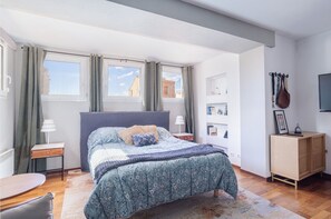 Una camera da letto con un letto, comodini, una scrivania, una sedia, un armadio e una televisione.