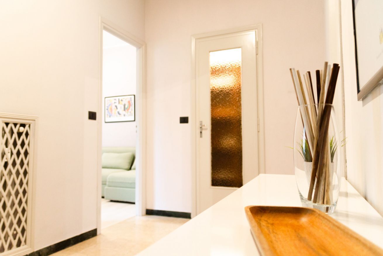 A hallway with a white door, a wooden tray, and a vase with sticks.