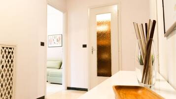 A hallway with a white door, a wooden tray, and a vase with sticks.