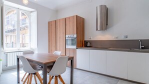 Eine moderne Küche mit einem Holzespeisetisch und -stühlen, einem eingebauten Backofen und einer Edelstahl-Dunstabzugshaube.