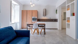 Eine moderne Küche mit Holzschränken, einem Esstisch mit Stühlen und einem eingebauten Backofen.