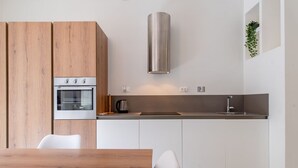 Eine moderne Küche mit Einbauofen, Edelstahl-Dunstabzugshaube und minimalistischem Design.