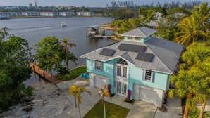 A house with a garage, solar panels, and a dock by a lake. - Avion Park Luxury Home | Waterfront • Private Dock • Modern 3BR Naples (Naples)
